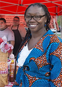 Angela Bannerman Ankoma stands beneath a red umbrella at the Sankofa Market