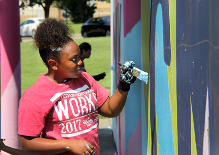 A volunteer helps paint a mural in Camden, New Jersey