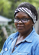 Sandra Robertson is a black woman wearing glasses and a denim shirt