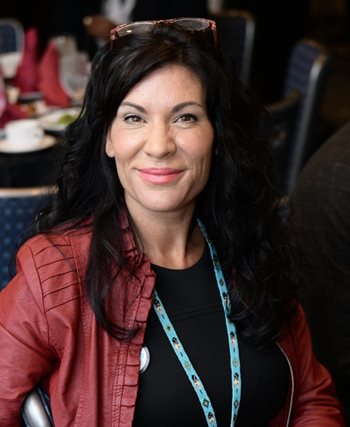 Chrystel Cornelius smiles at the camera. She is wearing a red jacket.