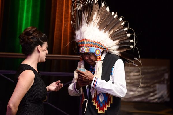 Chrystel Cornelius talks with a man in full headdress.