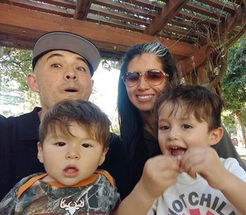 A Latino family sits outside of their new home in California