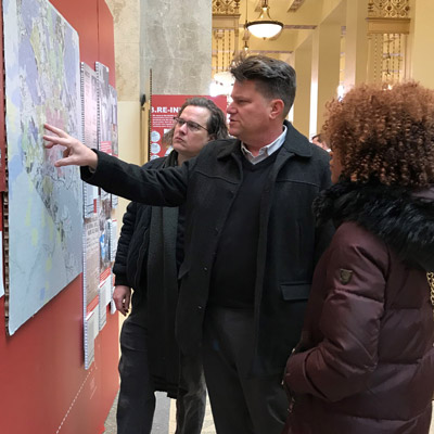 Three individuals look at a redlining map as part of the Undesign the Redline exhibition