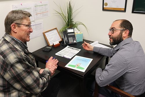 Jeff Belzer helps with some one-on-one coaching, sitting across from a man who wears glasses.