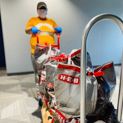 A volunteer pushes a cart filled with food.