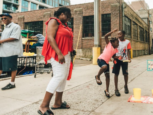 Kids play on the sidewalk after participating in a creative activity meant to encourage their imagination and youth leadership