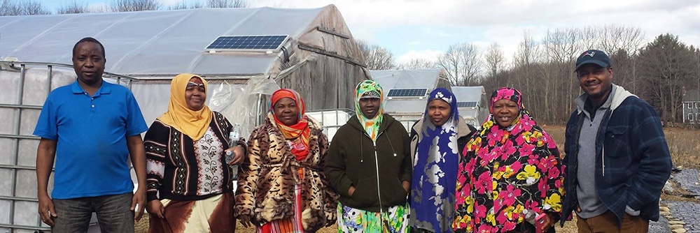 Farmers stand near Fresh Start Farms, staring directly at camera and smiling.