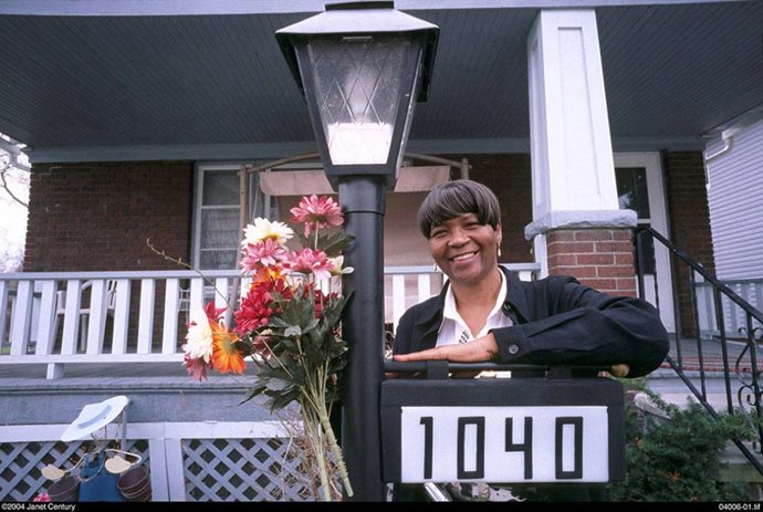 A black woman stands next to a street light in front of her home