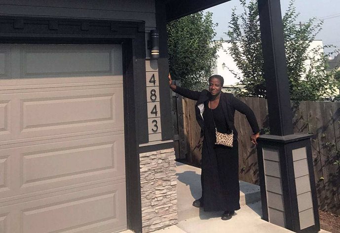 Charlene McGee, a black woman, stands in front of her new home