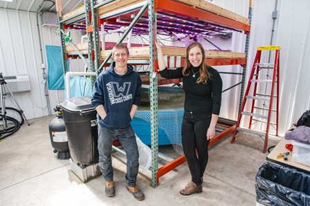 Two VISTA members stand in front of a shelving unit