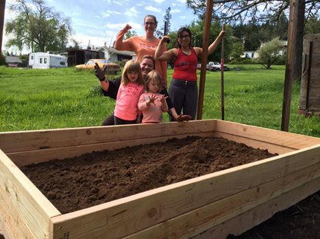 Two white girls and three white women stand in front of a plot of dirt