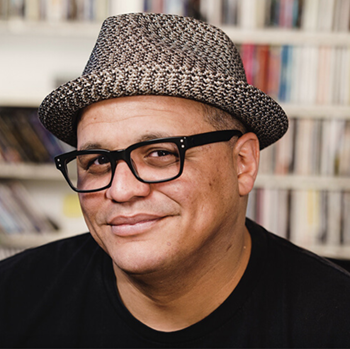 Billy Palmer smiles, wearing a straw hat and glasses.