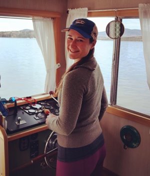 Rheanna stands near a ship's wheel.