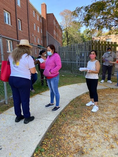 People stand near a testing site, with Preeya holding a clipboard.