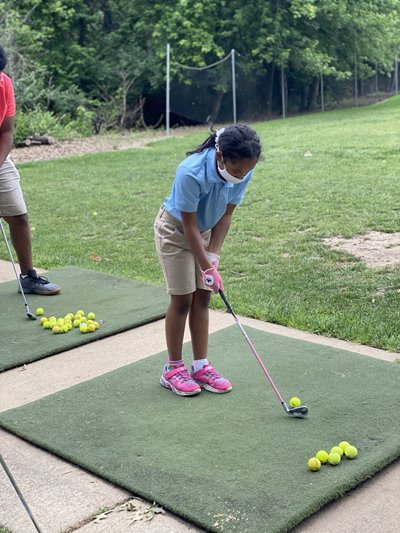 A young girl gets coaching on her golfing swing..