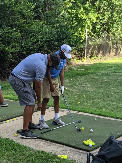 A golf coach works with one of the students in the Better Family Life program.