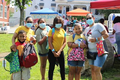 A group of kids and their grownups show off their backpacks at Lawrence Community Works.