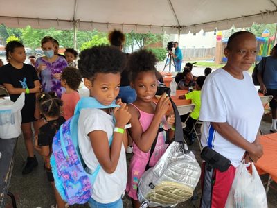 Two young girls clutch new backpacks.