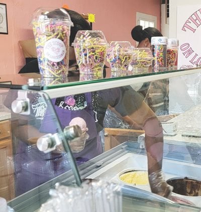 A young woman works in the ice cream shop.