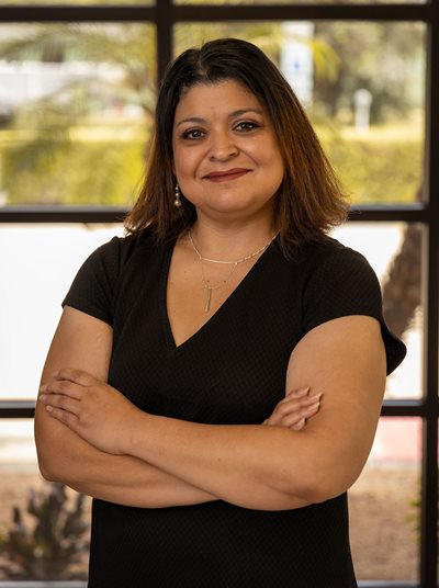 Myra Martinez stands with her hands folded in front of a window.