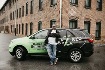 A driver leans against a car for the veterans transportation program.