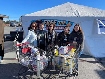 A group of donors stand with shopping carts full of turkeys.