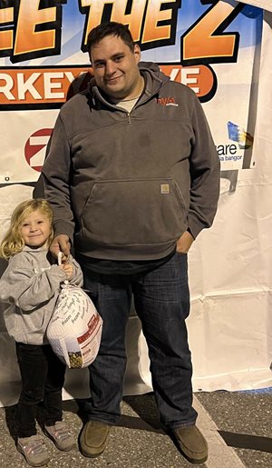 A girl and her father stand with a turkey.