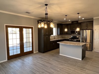 The interior of a new home, shows the dining room and kitchen, with hanging lights.