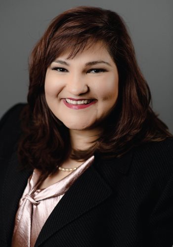 Marietta Rodriguez smiles against a gray background.