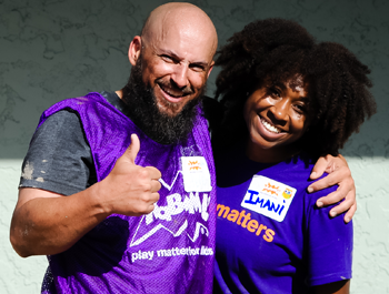 A bearded veteran wearing a purple vest stands next to a black woman