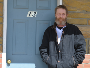 John Graves, a resident of Beacon Apartments, standing outside of his home with the door in the background.