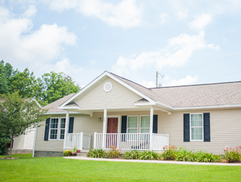 A manufactured home with tan siding and a white porch