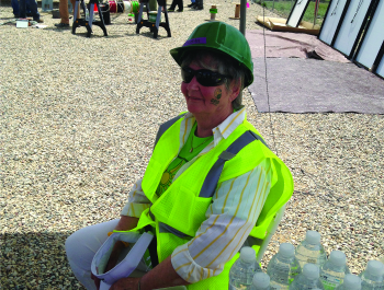 A woman sitting outside wearing construction gear.