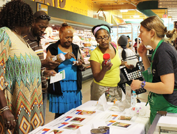 Three black women and one black man stand at a food sample table