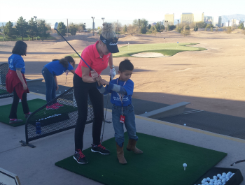 A young woman teaching a child to golf.