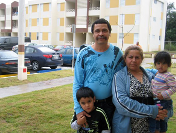 A family of four stand in front of a newly-constructed apartment building