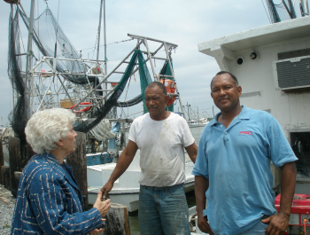 Two men and an elderly woman talking to one another at a shipyard.