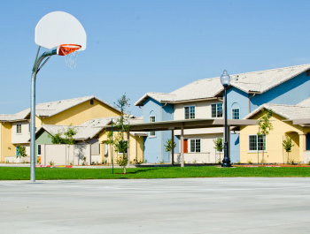 A basketball court with houses in the background.