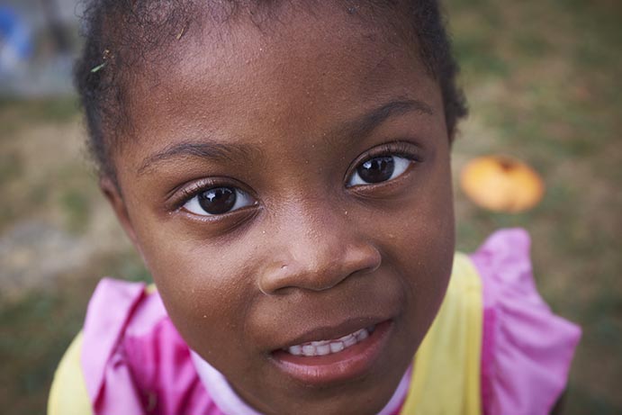 A little black girl wearing a pink and yellow dress