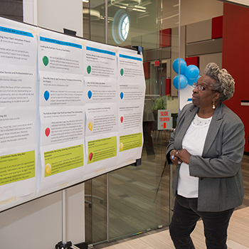 A Black woman stands in front of a whiteboard that features guidance on becoming a volunteer