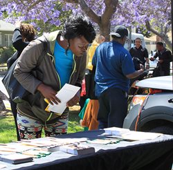 Black woman examines the Loan Scam Modification alert materials on a table outside