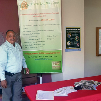 A Puerto Rican man stands at a red table with information about community safety