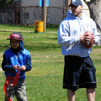 A local police officer holds a football next to a local kid wearing a red flag