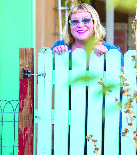 A woman stands behind a bright green fence