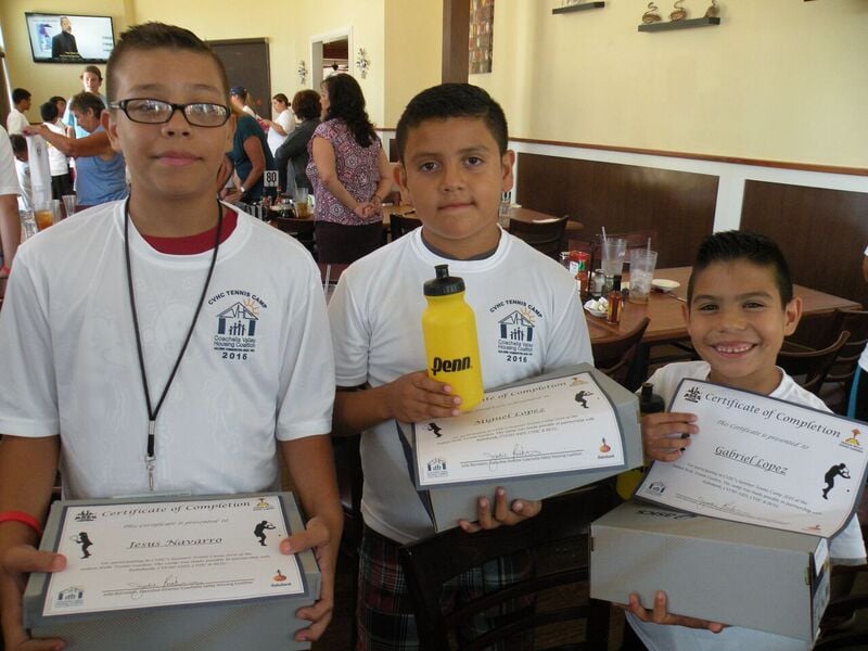 Three young boys wearing white sweatshirts hold certificates of completion