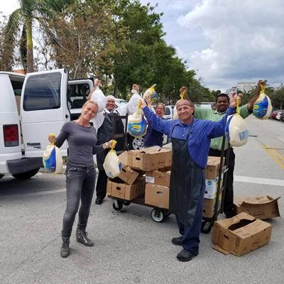 Volunteers holding bags of turkeys standing outside near parked trucks